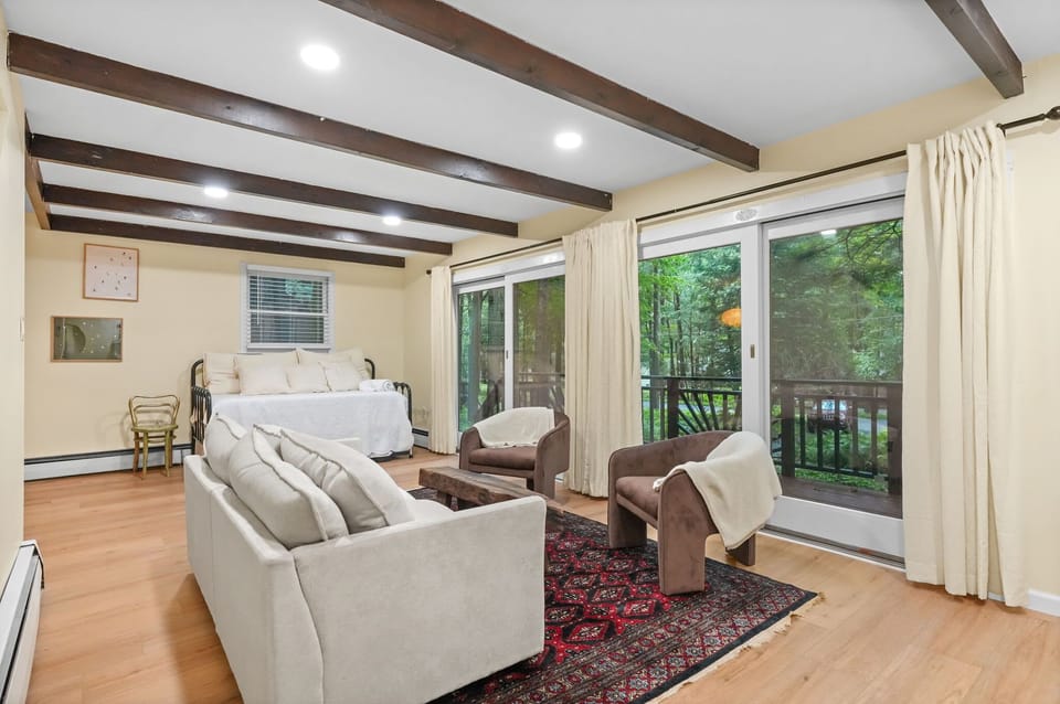 Den lounge with sofa, accent chairs and forest-facing sliding doors
