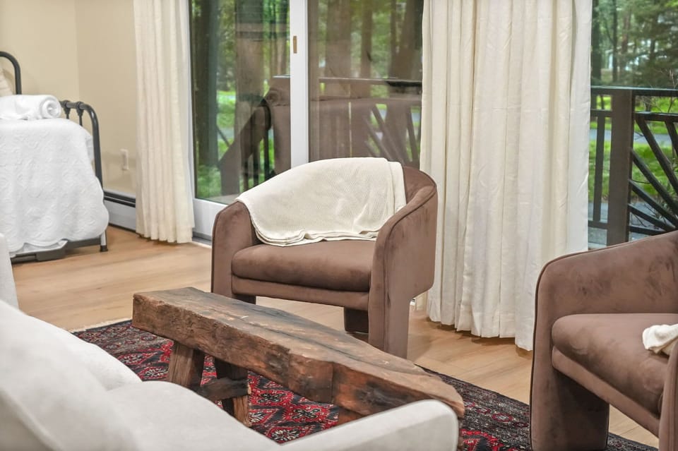 Deck access from the den — velvet lounge chairs and a reclaimed wood bench