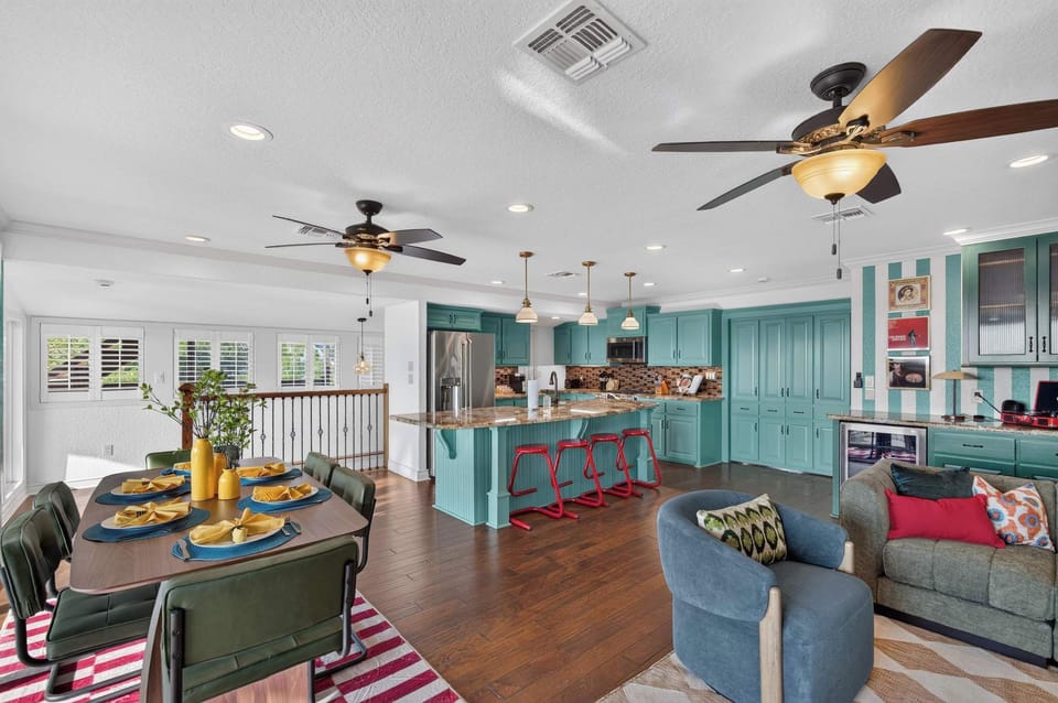 Experience effortless entertaining in an open-concept living space that combines a fully equipped teal-accented kitchen, an inviting dining area, and a cozy lounge setup under one roof.