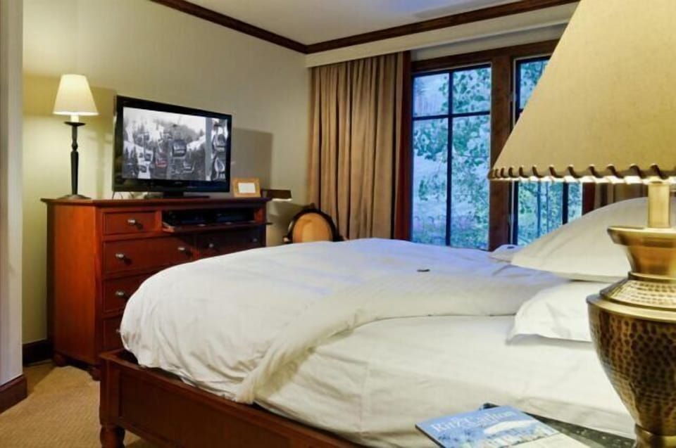 Cozy bedroom with plush bedding, TV, and peaceful window views