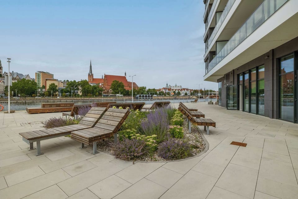 A spacious terrace features outdoor seating overlooking the waterfront. The open space is perfect for relaxing in the fresh air.