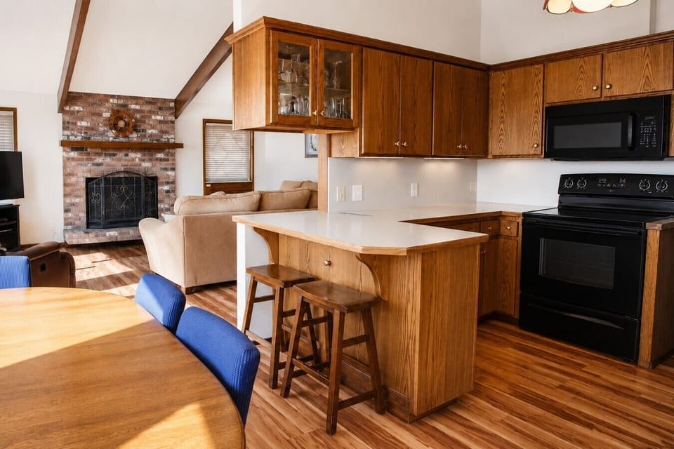 An open-plan kitchen and living area with a breakfast bar, stone fireplace and hardwood floors keeps the whole group together.