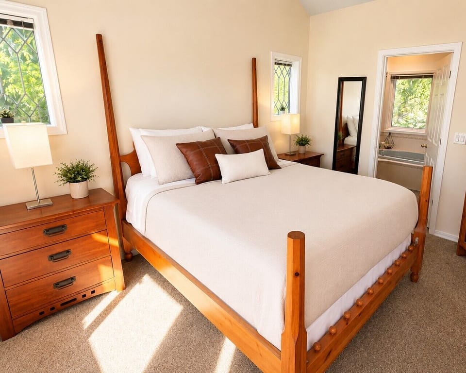 Bright and inviting bedroom with a comfortable bed, crisp white linens, warm wood furnishings, and natural light.