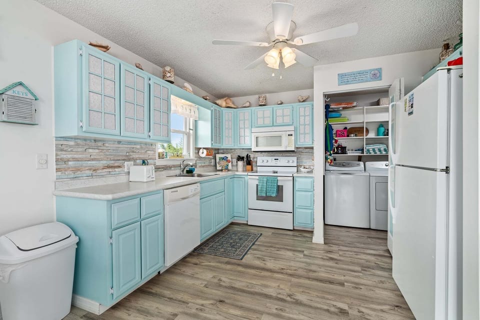 The kitchen features a beach‑cottage chic design, blending light coastal colors with a warm, inviting layout.
