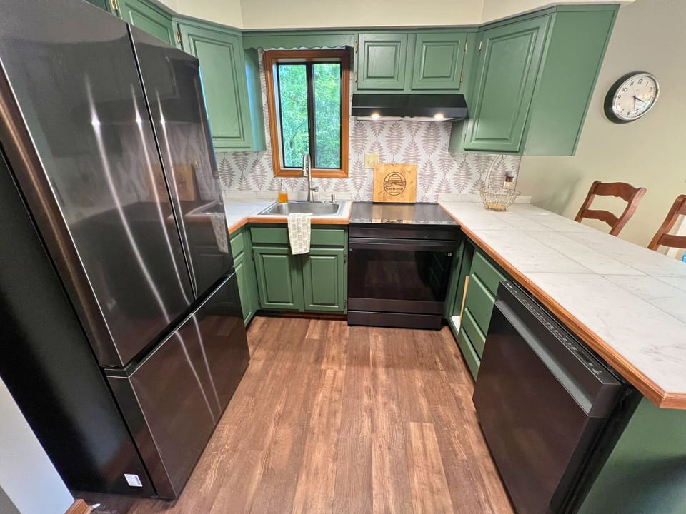 Updated green kitchen cabinets with new appliances.