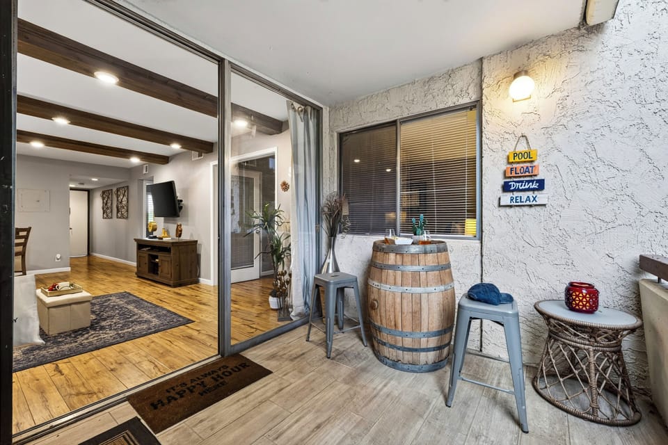 Covered balcony featuring rustic wine-barrel tables and outdoor seating.