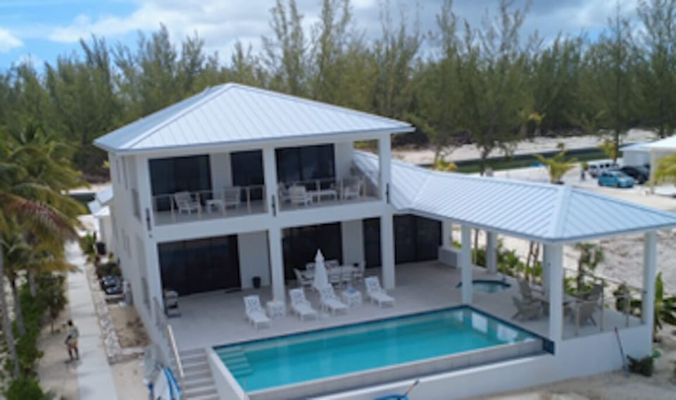 Beachfront view of back of villa, pool hot tub, covered porches and marina