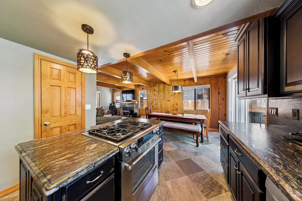 Gourmet kitchen with granite countertops, professional-grade gas range, and wood accents. Gather around the rustic dining table to cook and create lasting memories.