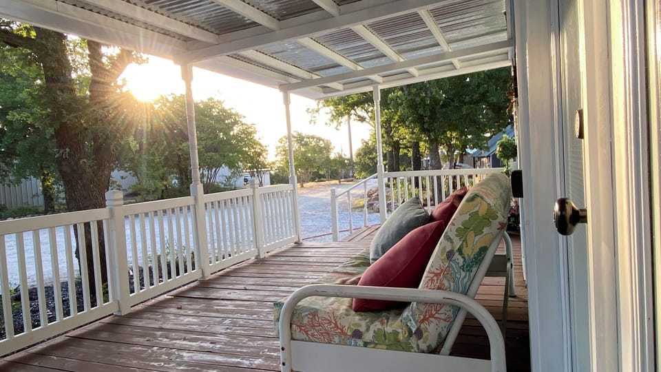 Sunny covered porch with cozy seating and peaceful tree-lined views