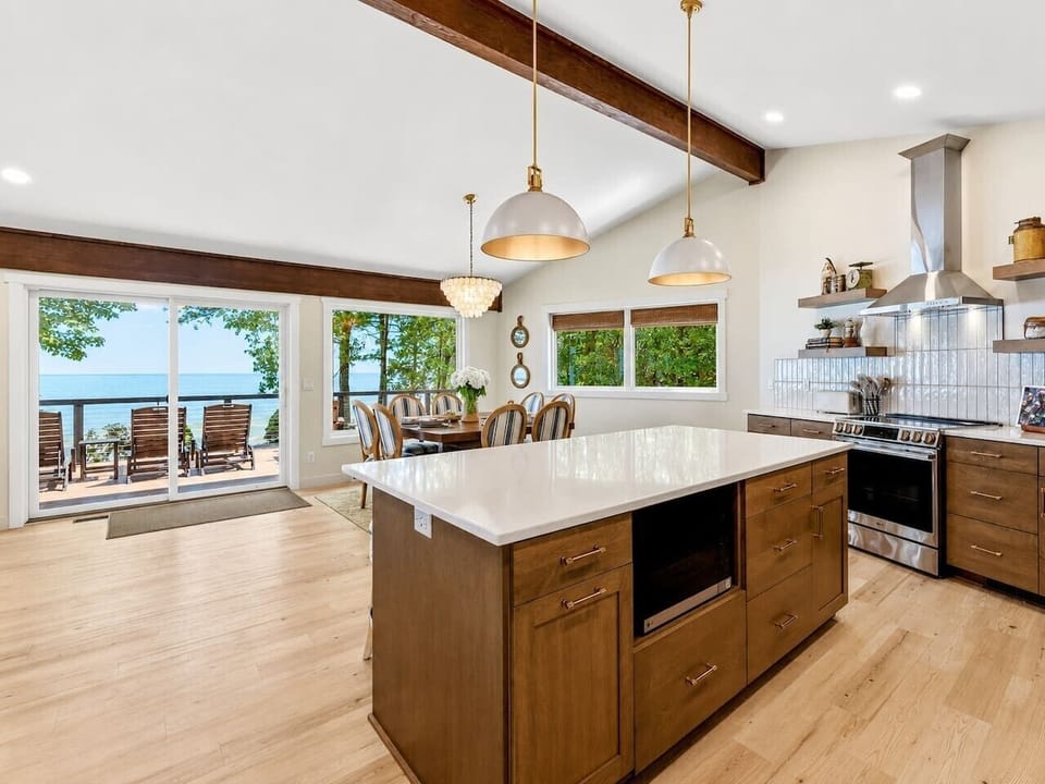 The fully equipped kitchen centers on a large island with seating for four and direct sightlines to the deck and lake.