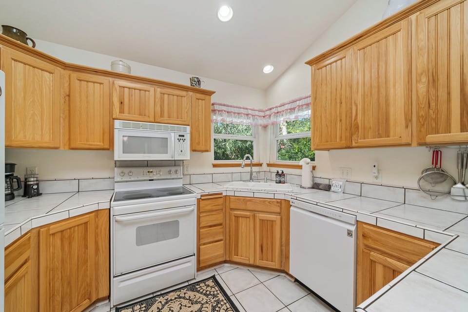 Your kitchen is bright and spacious, with warm wood cabinetry and ample counter space for meal prep. Natural light pours in through the window above the sink, making it a welcoming spot to cook and gather.