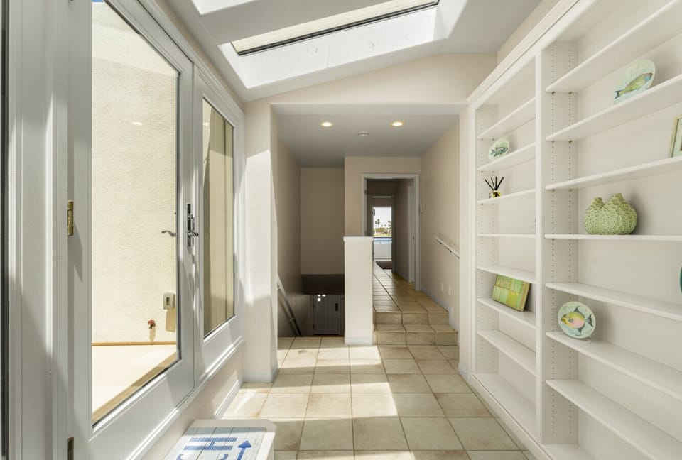 Bright hallway with skylights, custom shelving, and seamless indoor-outdoor flow.