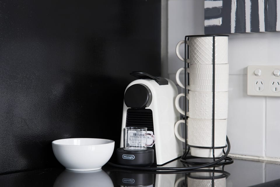 Modern coffee station with pod machine and stylish stacked mugs