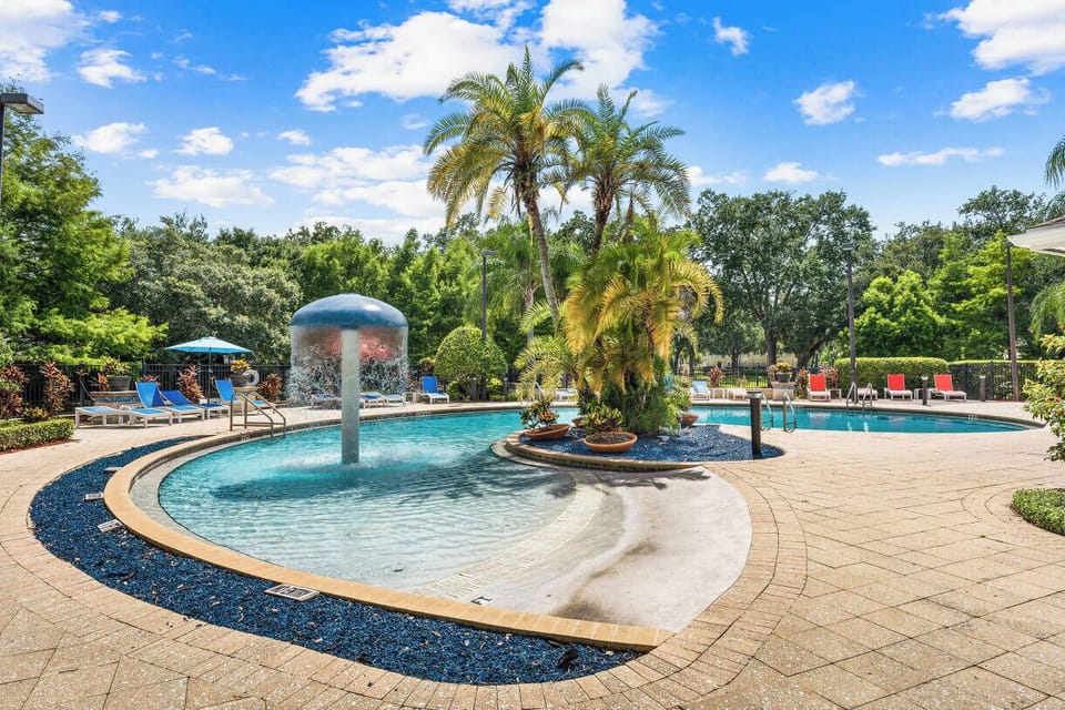 Resort-style pool with tropical landscaping and fun splash fountain