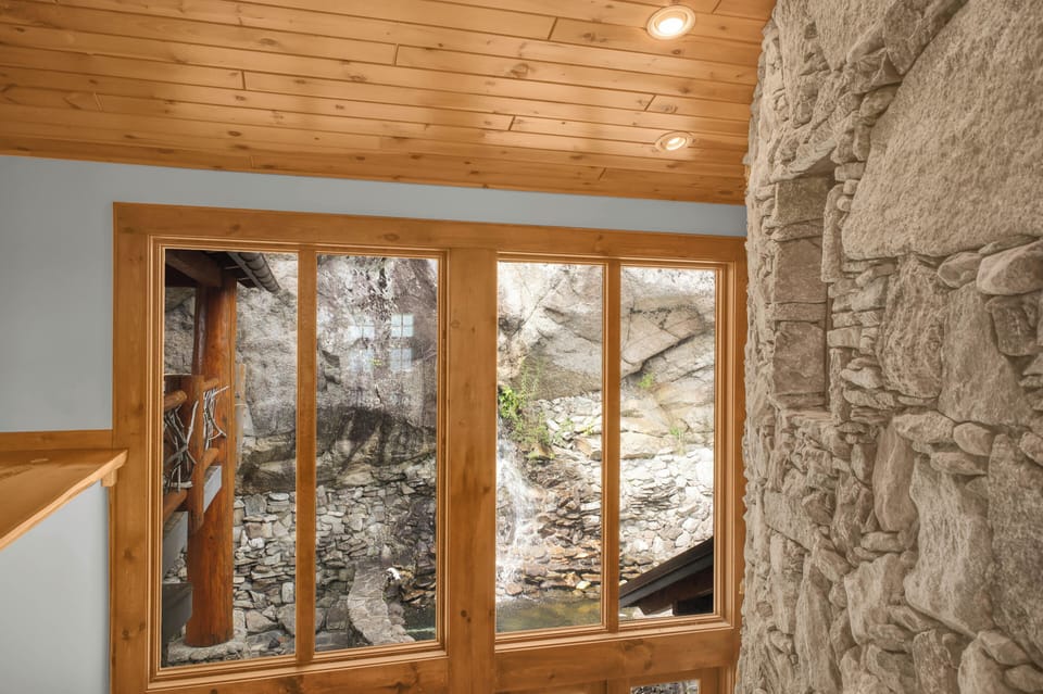 The 60-foot waterfall tumbles down the granite cliff face right outside the window, a private water feature no other cabin can claim.