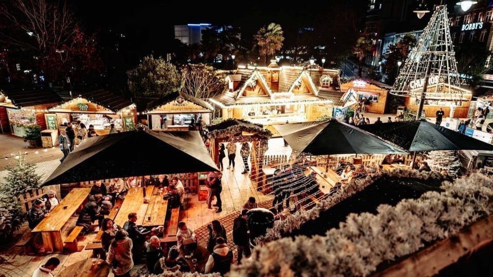 Festive night market with cozy chalets, lights, and lively dining