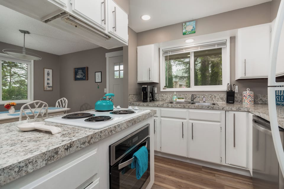 Step into your fully equipped kitchen with granite countertops, modern appliances, and natural light streaming through large windows overlooking lush greenery—perfect for preparing meals at home.
