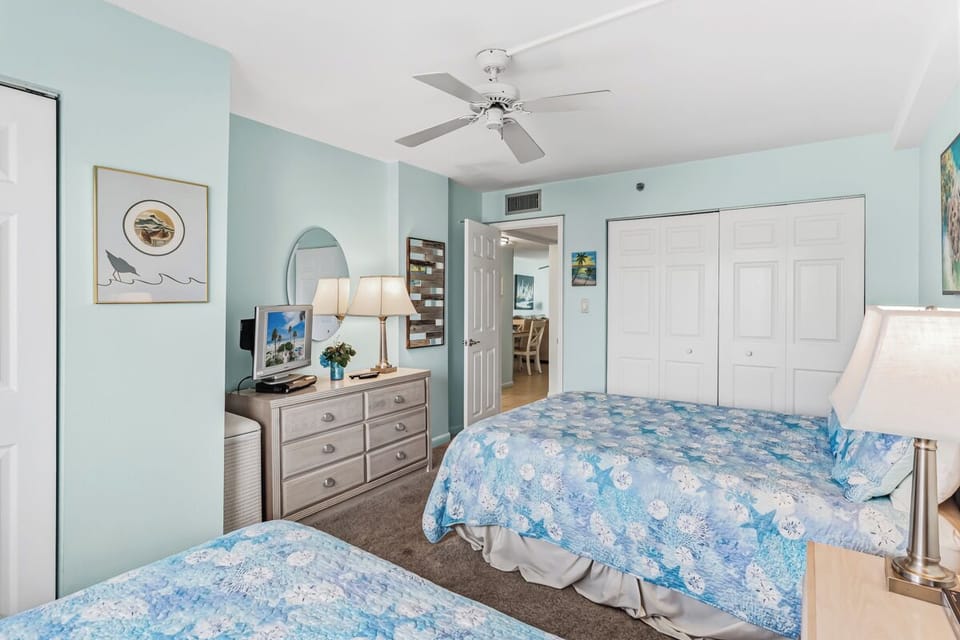 Drift off in this serene coastal bedroom, where soft sea-blue tones and gentle breezes from the ceiling fan help you unwind. Twin beds and ample storage make your stay effortlessly comfortable.