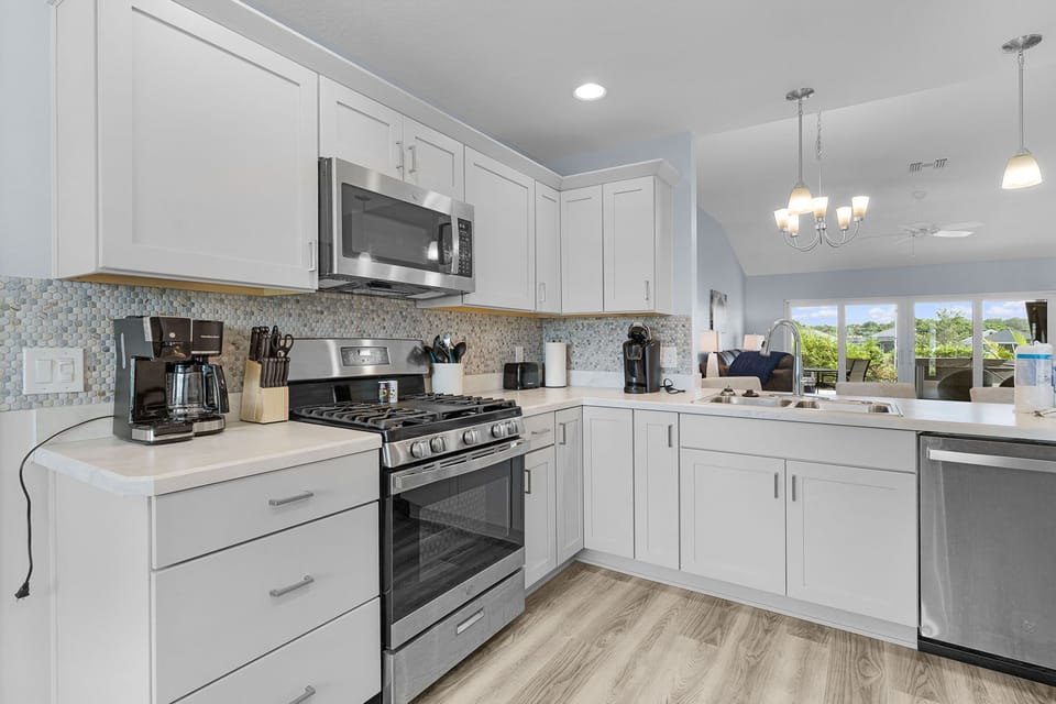Step into your bright, fully equipped kitchen with modern appliances, elegant white cabinetry, and natural light streaming in from the dining area—perfect for whipping up your favorite meals.