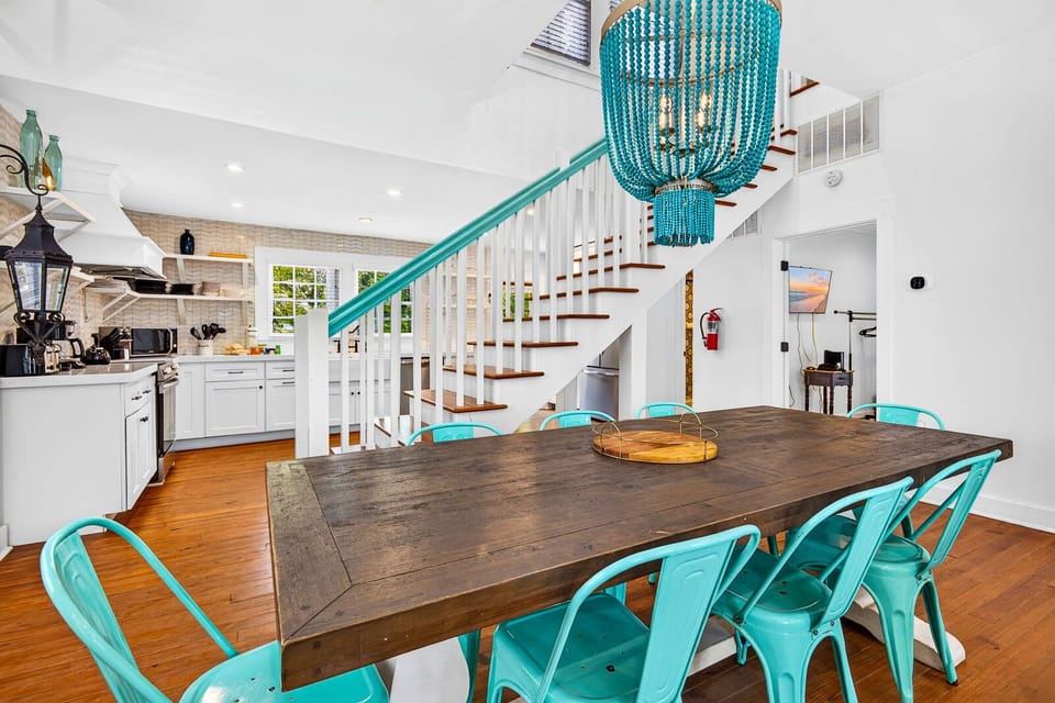 Bright dining space with rustic table, turquoise accents, and open kitchen