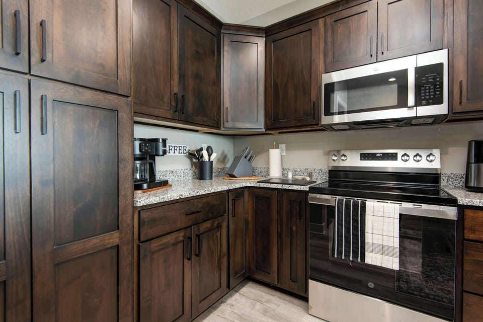 Modern kitchen featuring a stainless smooth-top stove and microwave, perfect for easy meal preparation, quick snacks, and convenient vacation dining.