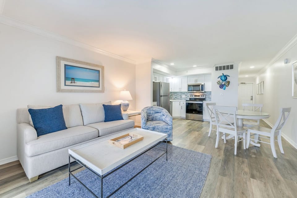 A dining table, couch, chair, and refrigerator share this open living and dining area.