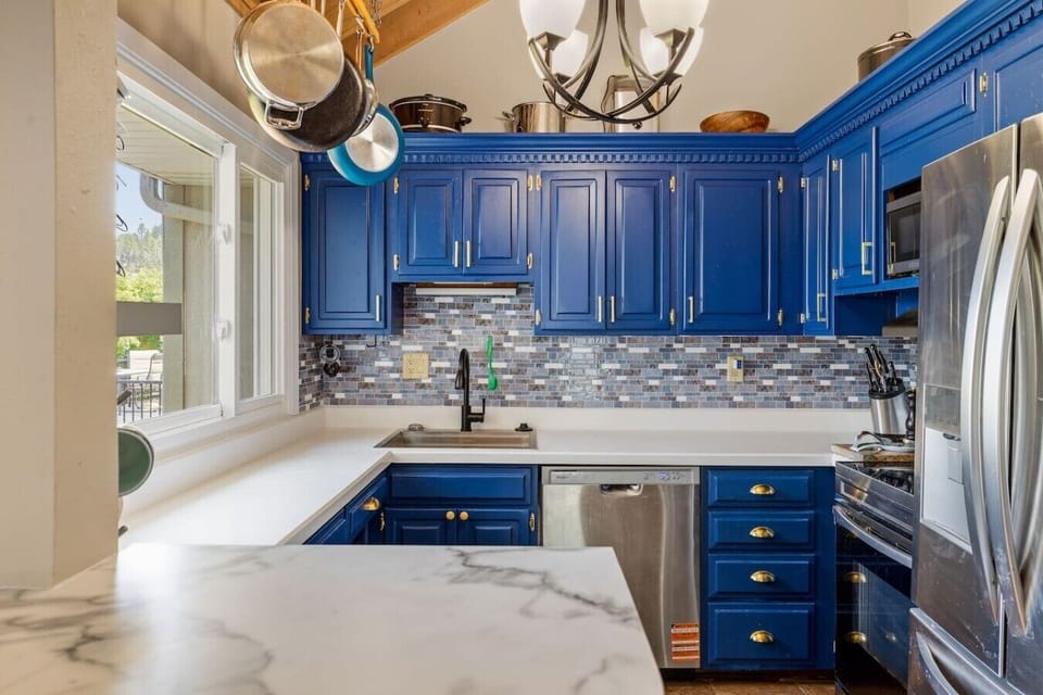 Modern chef`s kitchen featuring bold blue cabinets, stainless steel appliances, ample counter space, and everything you need to prepare meals during your stay.