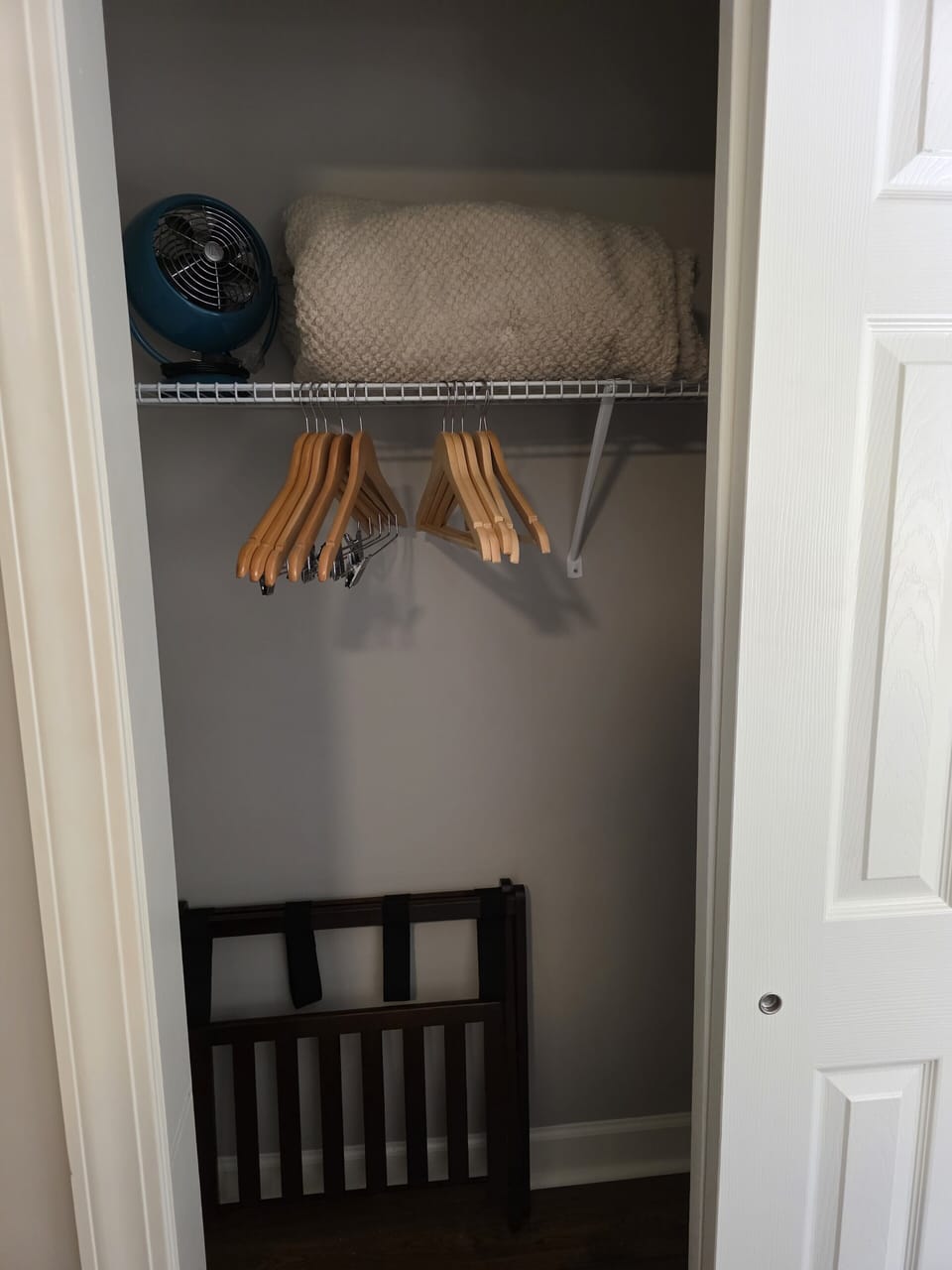 Queen bedroom closet with extra blanket, fan, luggage stand, and plenty of hangers.