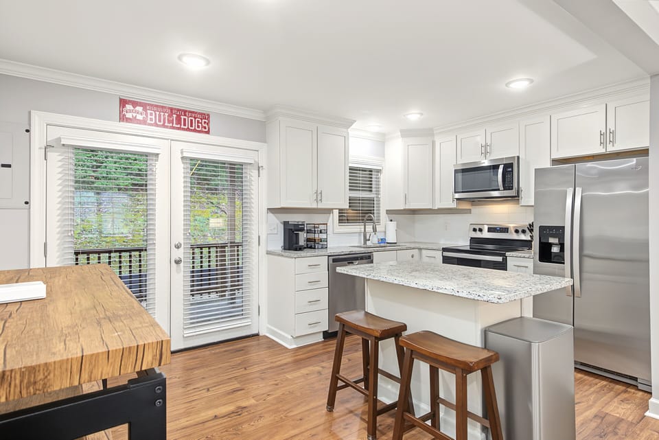Bright modern kitchen with breakfast bar, Keurig coffee maker, and deck access
