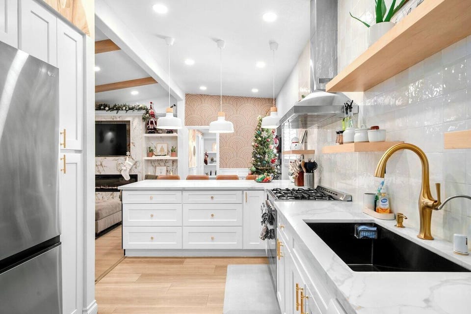 Create amazing meals with this modern kitchen featuring a spacious island, refrigerator, cooking utensils, integrated with a gas range and oven.