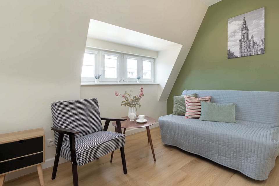 A comfortable sofa bed and an armchair create a perfect corner for relaxing. Large windows fill the room with natural daylight.