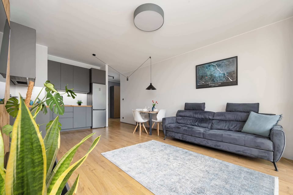 Looking across the open living space, the view encompasses the dark grey kitchen cabinets, dining area, and plush sofa resting on an area rug.