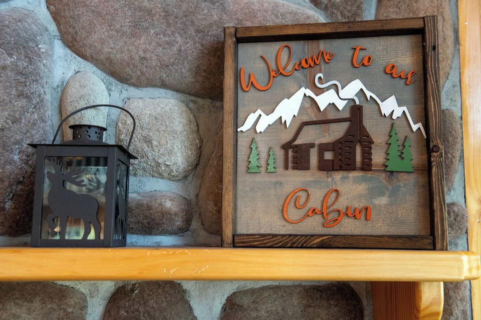 A hand-carved 'Welcome to our Cabin' sign sets the tone the moment you walk in — warm, woodsy, and ready to feel like home.