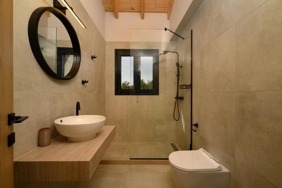 Modern bathroom with a spacious walk-in shower, vessel sink, warm wood vanity, and sleek contemporary finishes.