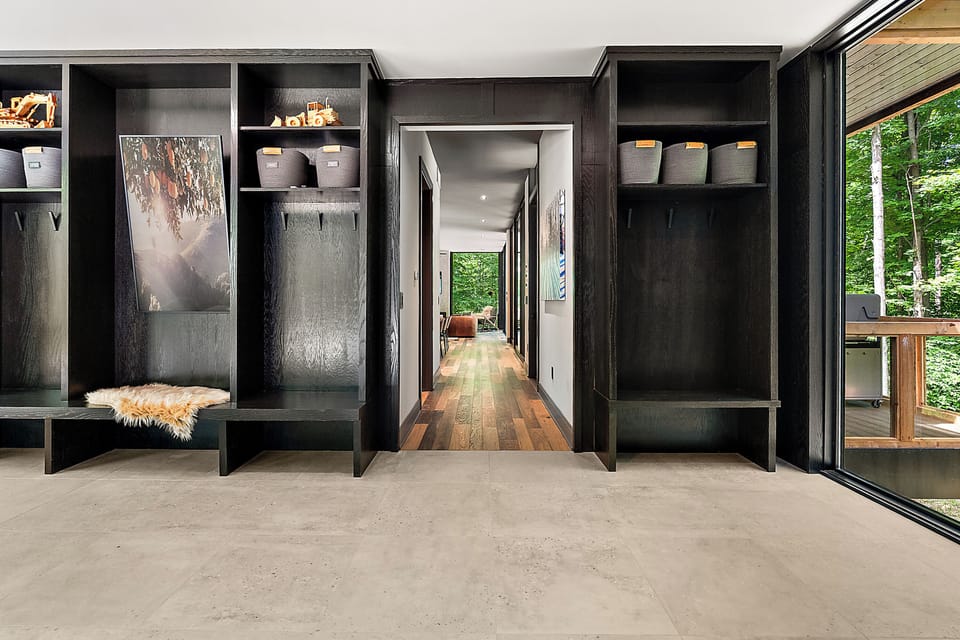 Modern mudroom with custom storage and serene forest-view deck access