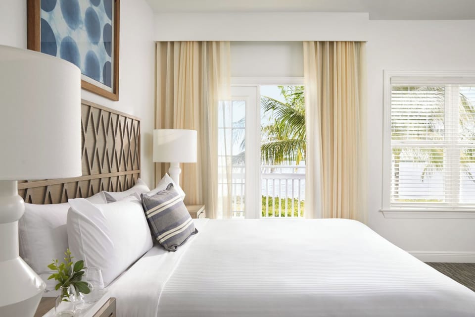 Sink into crisp linens beside soft drapes and airy windows.