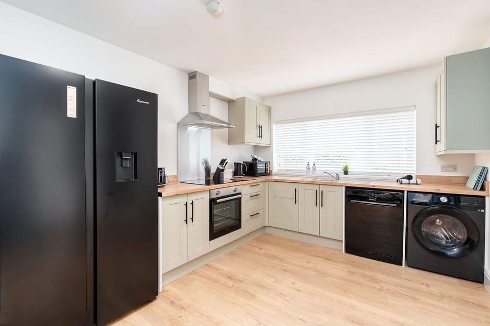 A spacious, fully equipped kitchen with a large fridge and freezer, dishwasher, washer-dryer, oven, kettle, and toaster.