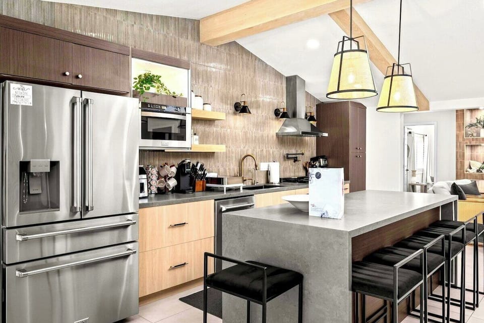 Modern kitchen equipped with breakfast island, refrigerator, oven and stove. 