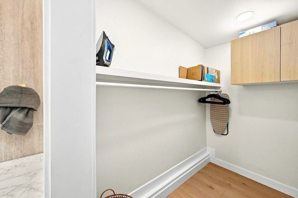 Closet, conveniently equipped with essentials like shelves, iron and ironing board, to store your belongings. 