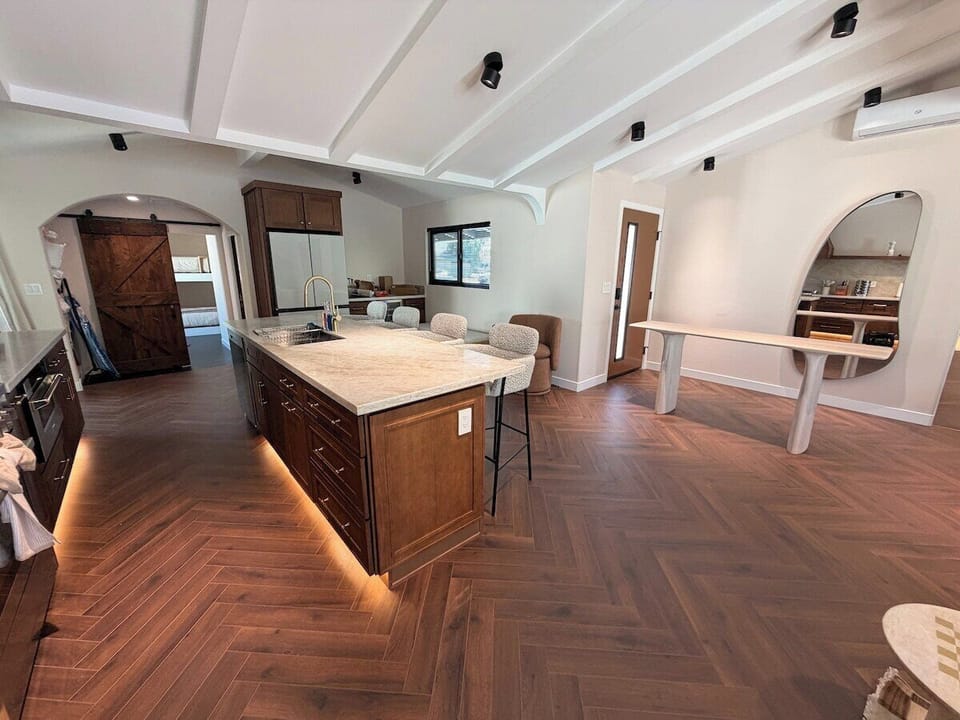 Experience sophisticated design in this beautifully appointed kitchen, complete with a massive stone island and elegant bar seating. A unique, organic-shaped mirror and sleek console table add a stylish touch to this open and inviting space.