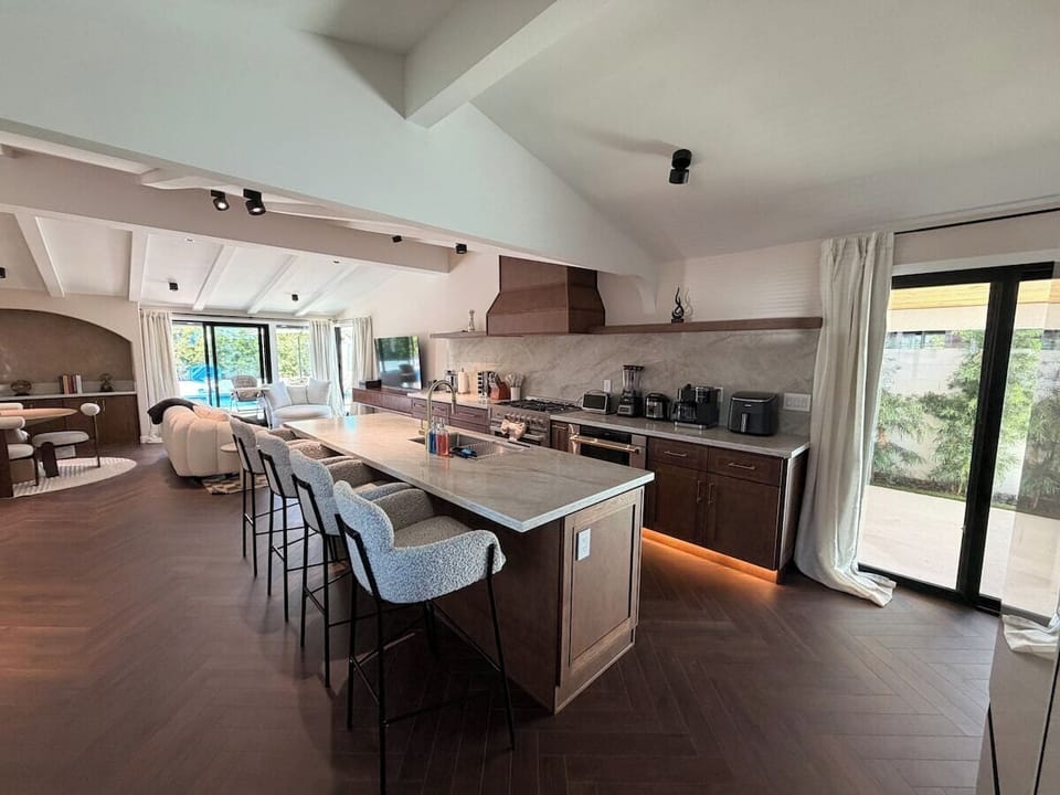 Elevate your culinary experience in this stunning kitchen, featuring a spacious island with bar seating and top-of-the-line appliances. The warm wood finishes, elegant lighting, and seamless design create an atmosphere for gathering and cooking.