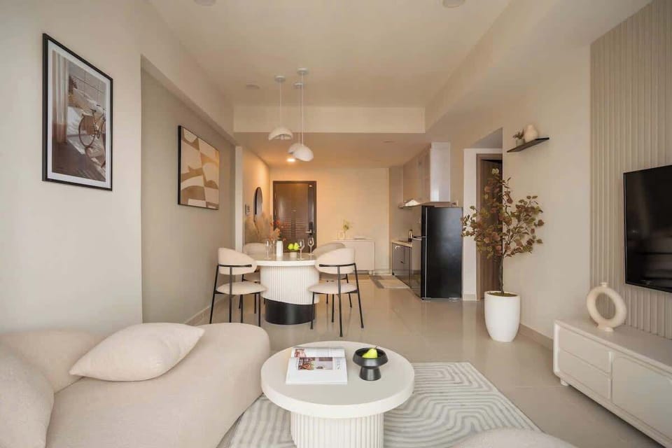 Open-concept layout with 2.5-seater lounge, round coffee table, 6-seat dining table, wall-mounted TV, high-speed Wi-Fi, and full kitchen. Perfect for relaxing, dining, or socializing together in one bright, flowing space.