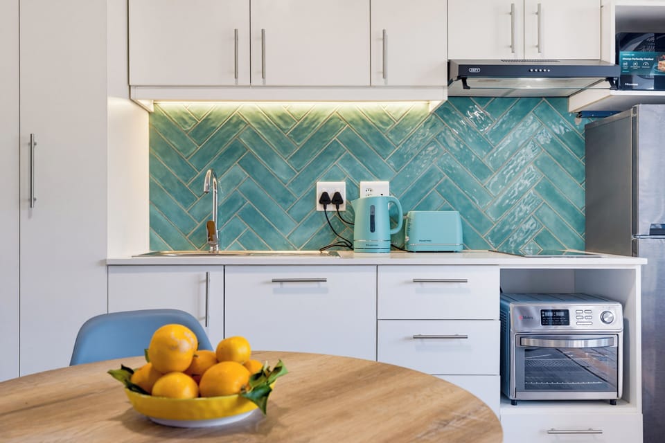 Stylish modern kitchenette with dining table and vibrant tile backsplash