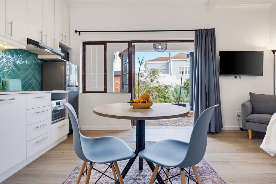 Bright studio with kitchenette, dining nook, TV, and garden courtyard access
