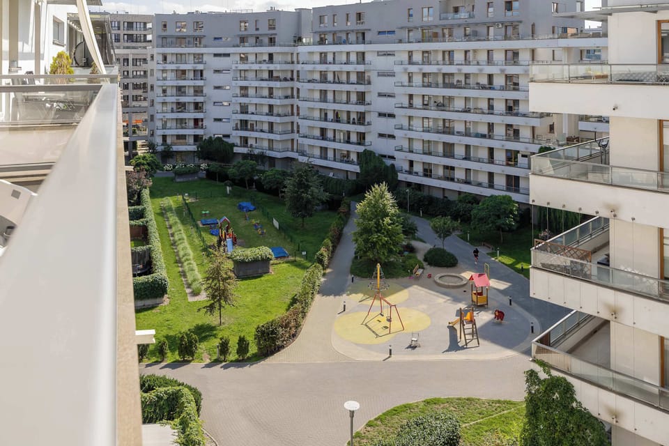 A view looking down into the apartment courtyard with landscaped gardens, pathways, and surrounding residential buildings.
