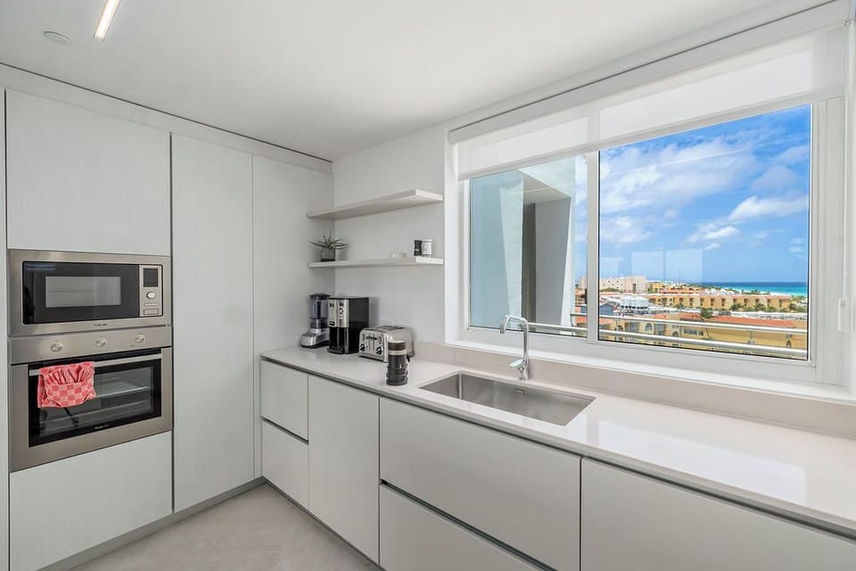 Prepare your favorite meals in this sleek modern kitchen, featuring full appliances, ample counter space, and stunning ocean views that make cooking a pleasure.