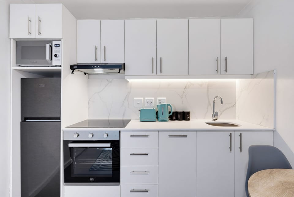 Bright modern kitchenette with oven, stovetop, and stylish dining nook