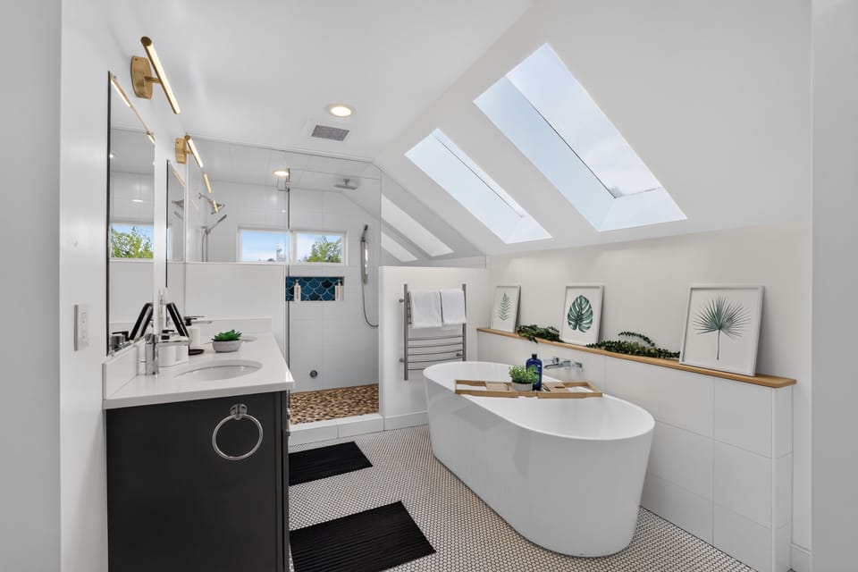 Modern bathroom featuring dual skylights, a freestanding tub, and a glass-enclosed shower.
