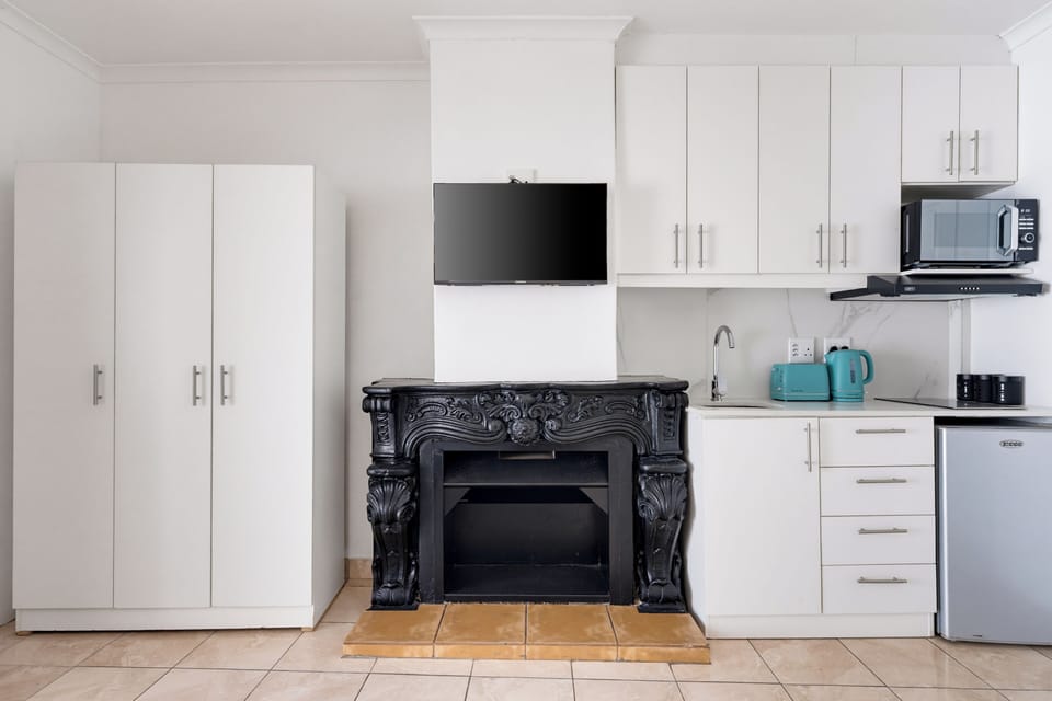 Compact studio comforts with kitchenette, TV, and elegant feature fireplace