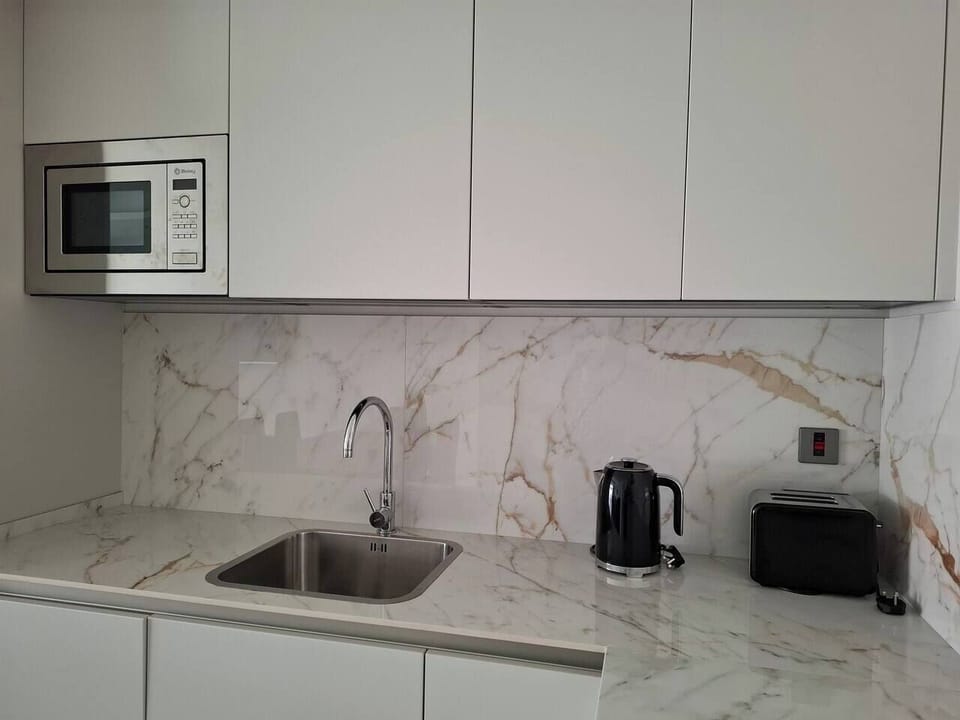 Modern, fully-equipped kitchen with marble-style backsplash. Includes an integrated microwave, dishwasher, kettle, and toaster. Everything you need for a convenient and high-end self-catering stay at Marina Club.